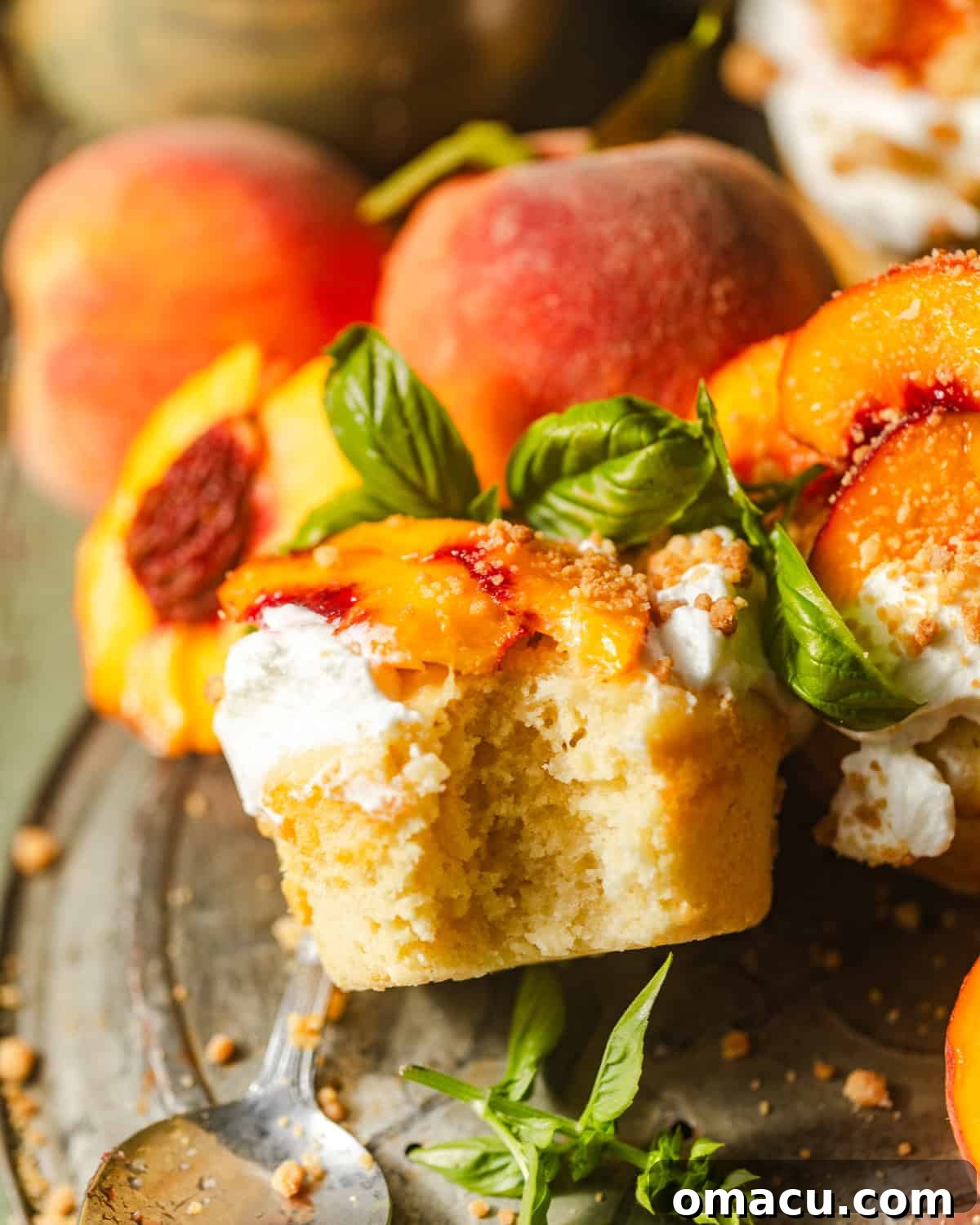 A single peach shortcake on a pie plate with a portion removed, revealing the soft, layered interior of cake, peaches, and whipped cream.