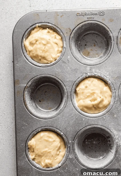 Golden-brown cake batter poured into a jumbo muffin tin, filling each cavity about two-thirds full.