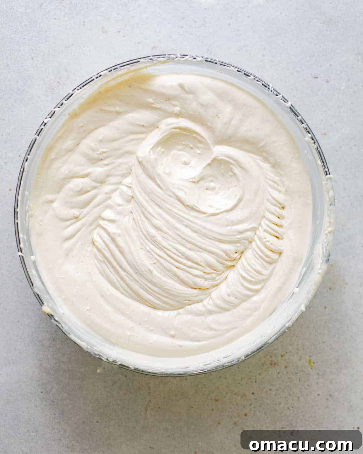 Freshly made whipped cream in a large mixing bowl, showing medium peaks, ready for assembly.
