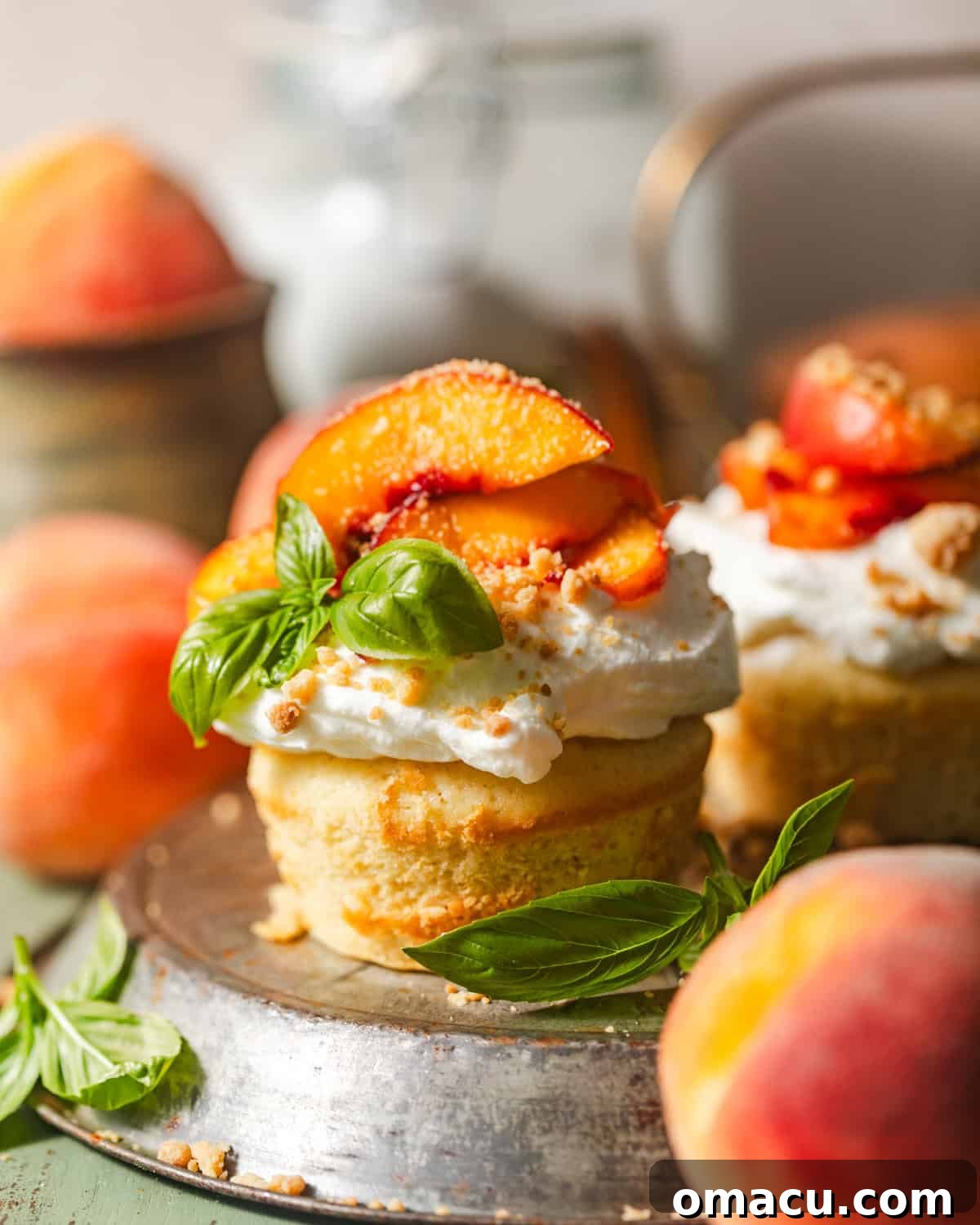 A fully assembled peach shortcake on a plate, layered with cake, macerated peaches, and whipped cream, garnished with cinnamon crumble.