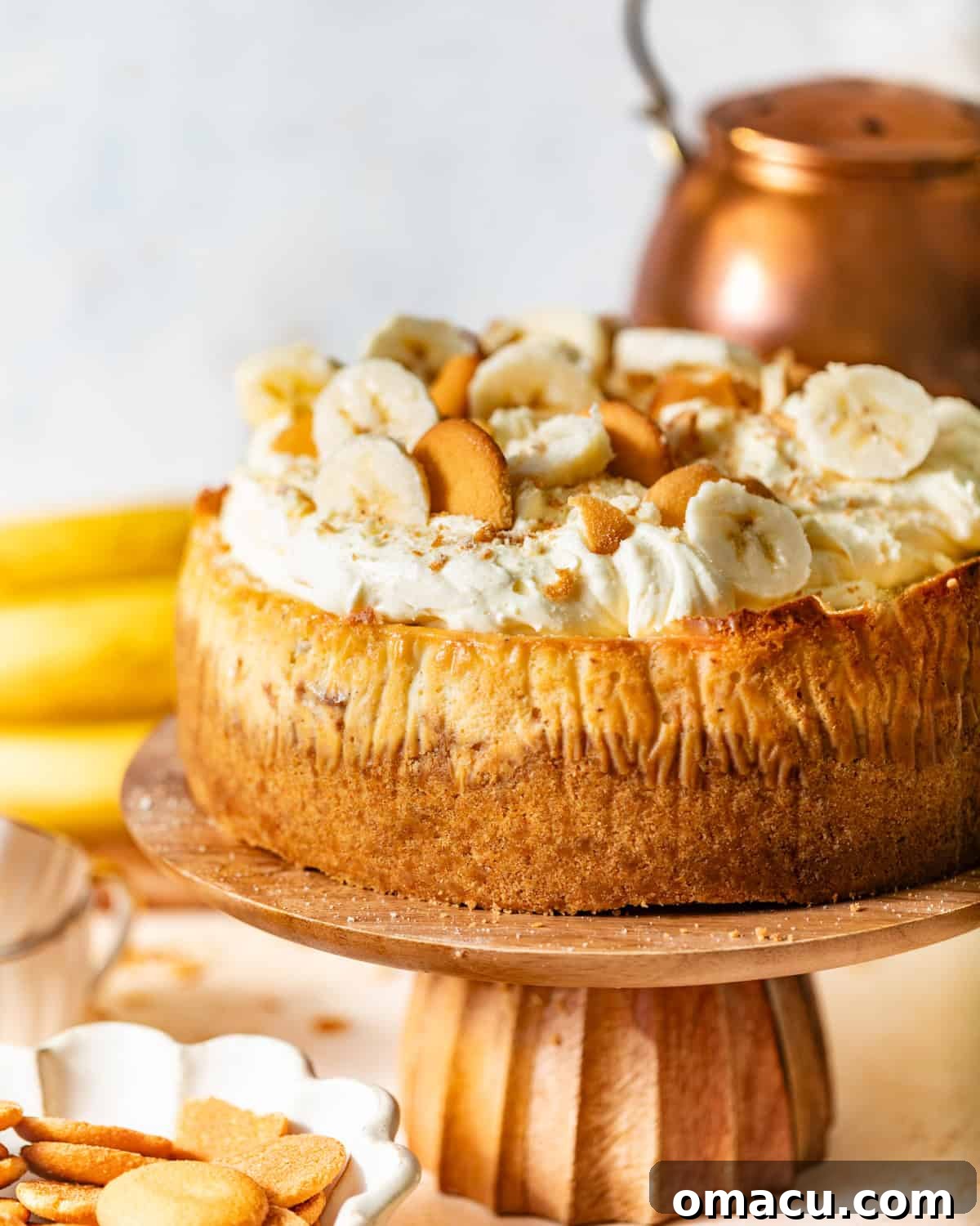 A stunning banana pudding cheesecake recipe presented on an elegant cake stand, garnished beautifully.