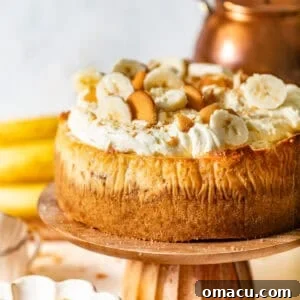 A decadent banana pudding cheesecake recipe on a cake stand, garnished for serving.