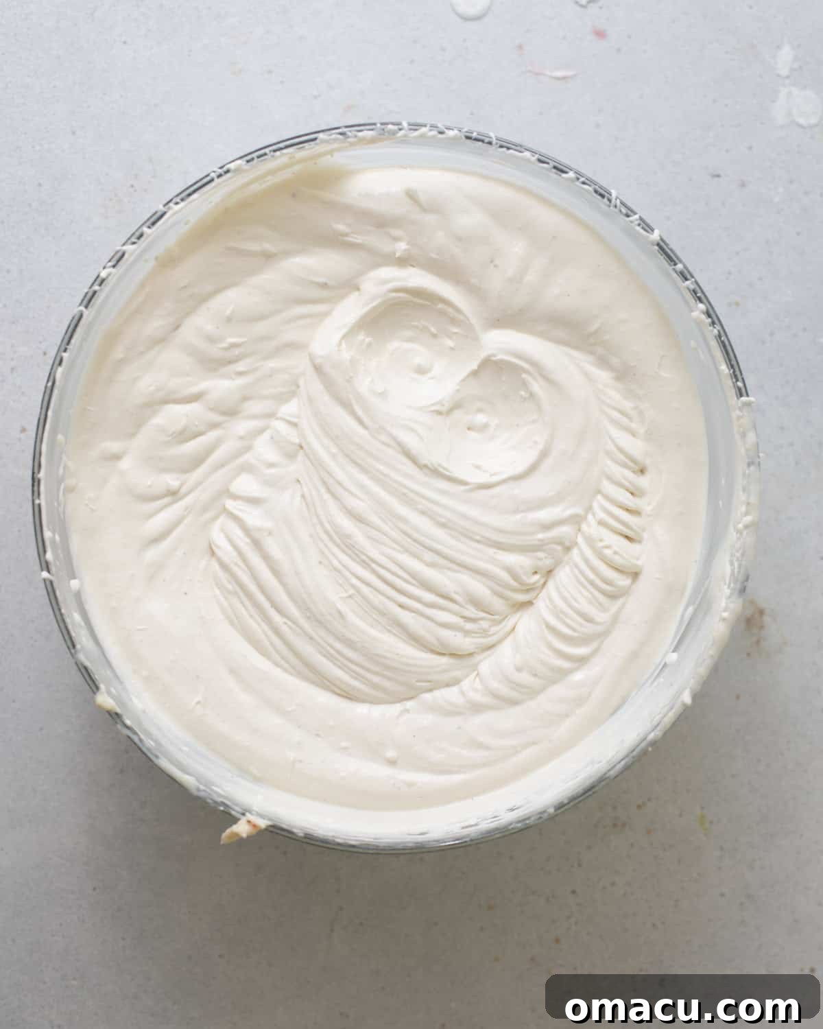 Fluffy banana cream whipped cream in a mixing bowl, perfectly stiff for topping the cheesecake.