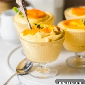 mango mousse in glass serving cups on a serving plate with spoons.