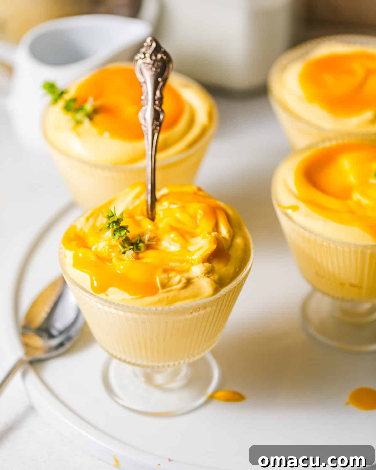 An inviting overhead shot of mango mousse beautifully presented in individual serving cups, garnished with fresh berries and mint.