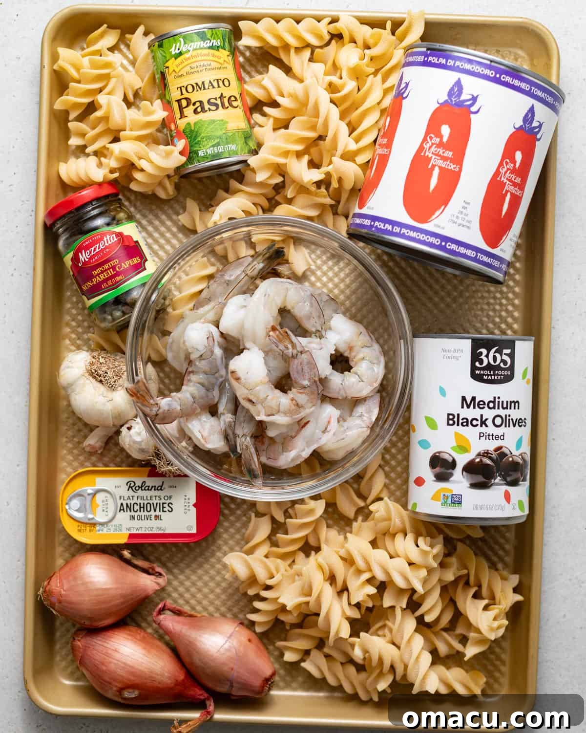 ingredients to make puttanesca with shrimp on a baking sheet.