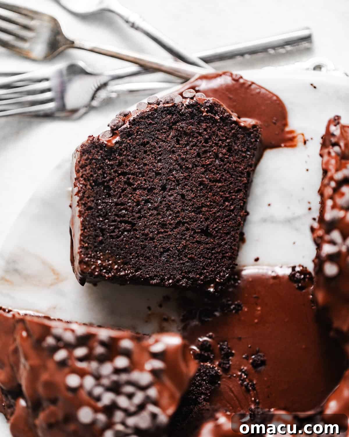 A beautifully presented slice of chocolate ricotta cake on a small serving plate, accompanied by forks, inviting a taste of its moist and rich interior.