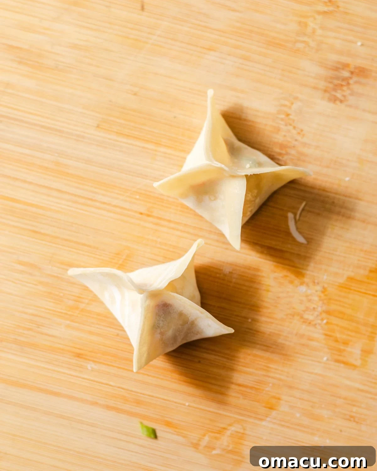 crab rangoons folded on a cutting board.