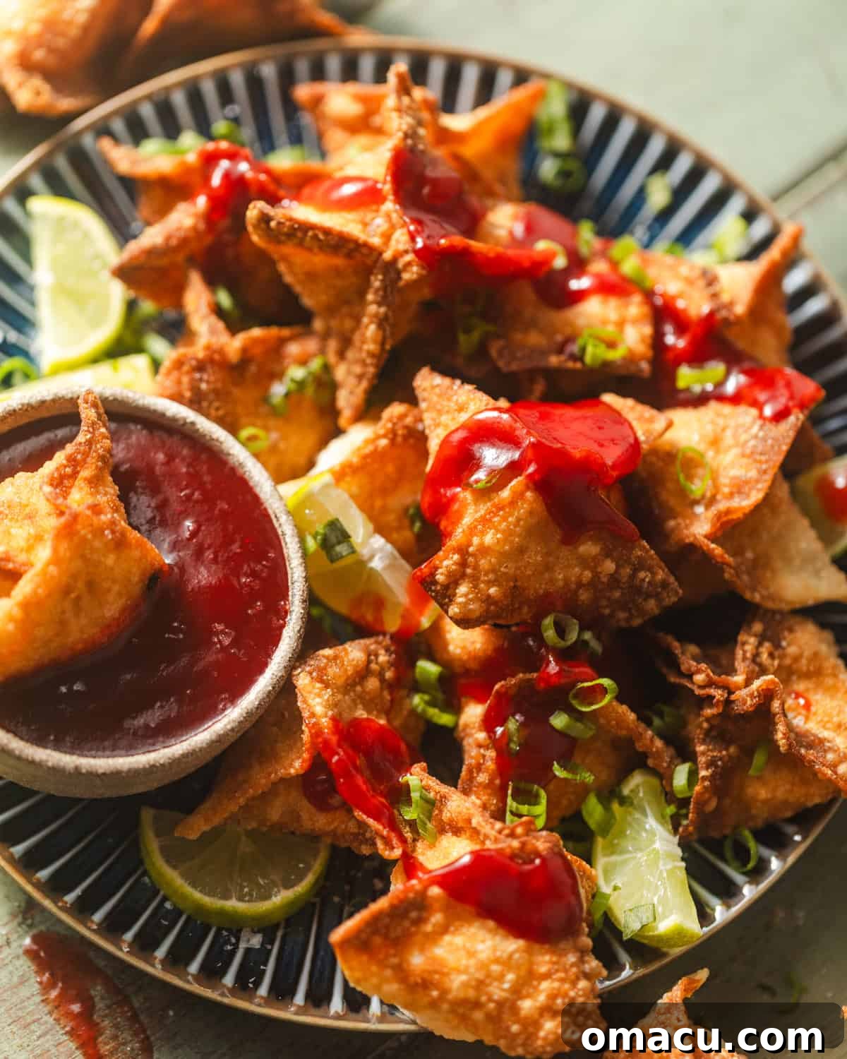 crab rangoons on a plate with scallions and limes.
