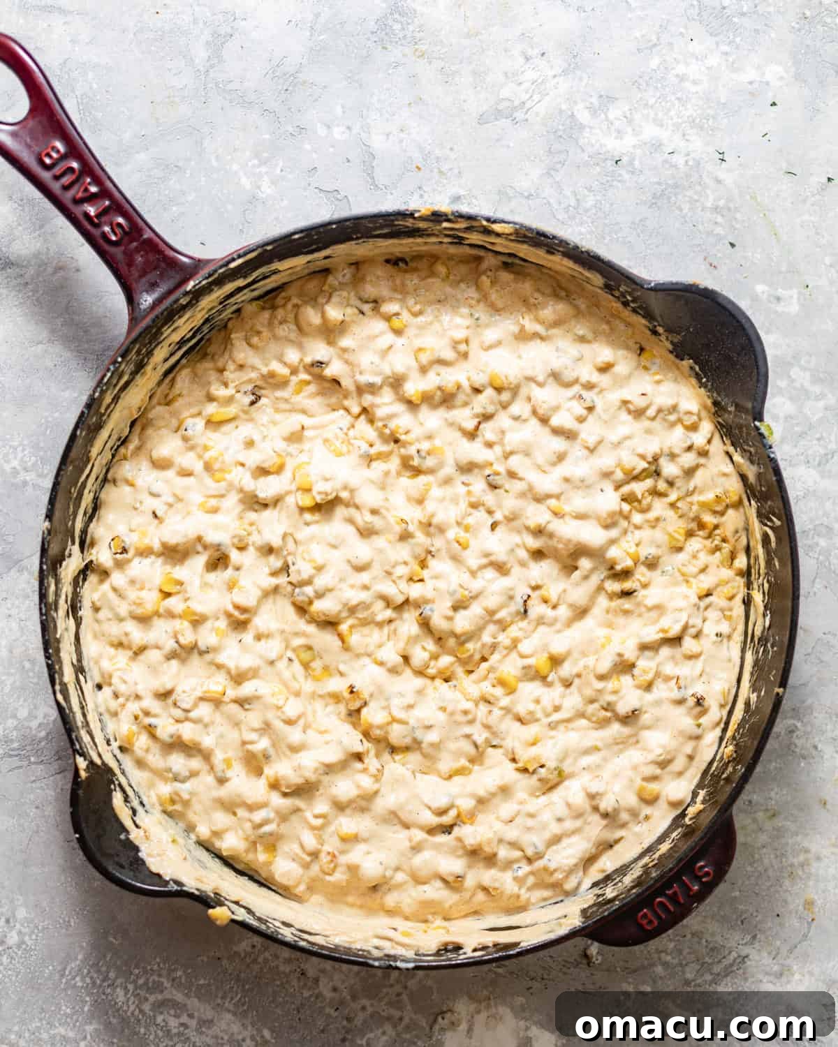 Melted cream cheese, pepper jack, mozzarella, sour cream, and mayo mixed with sautéed corn in a skillet.