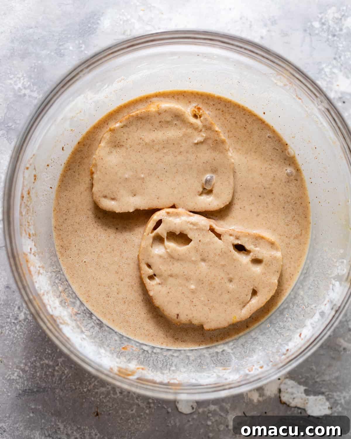 Thick, rustic slices of sourdough bread being carefully dipped into the rich, spiced custard mixture, ensuring full coating.