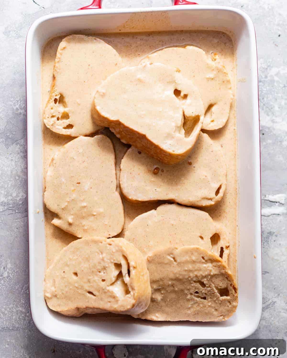 Sourdough bread slices soaking peacefully in a baking dish, completely immersed in the creamy custard base, ready for absorption.