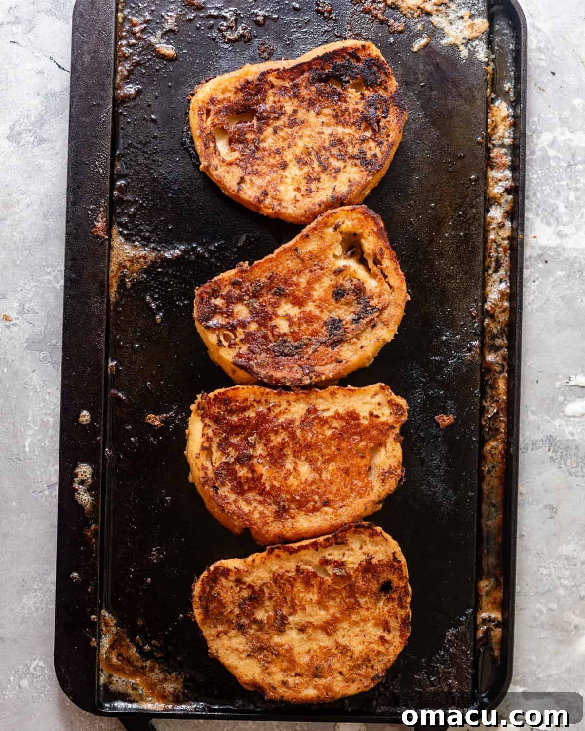 Sourdough French toast slices cooking on a hot griddle, developing a beautiful golden-brown crust and caramelization.