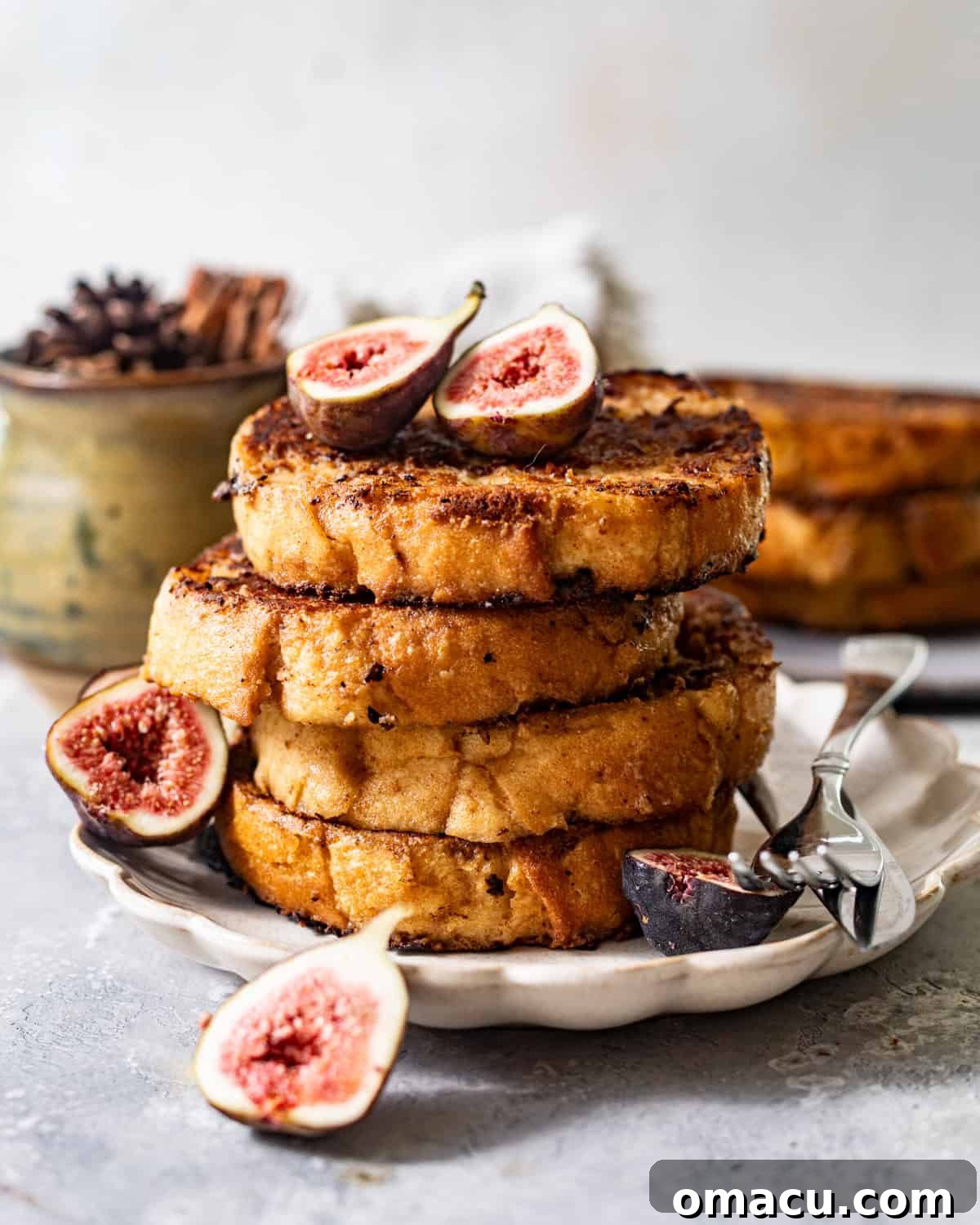 Beautiful stacks of golden sourdough French toast slices on a white plate, adorned with a light dusting of powdered sugar, ready to be served.