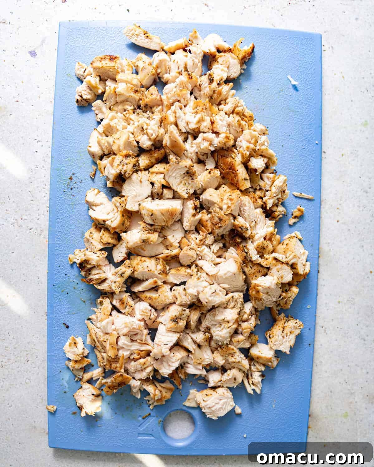 chicken cut into bite sized chunks on a cutting board. 