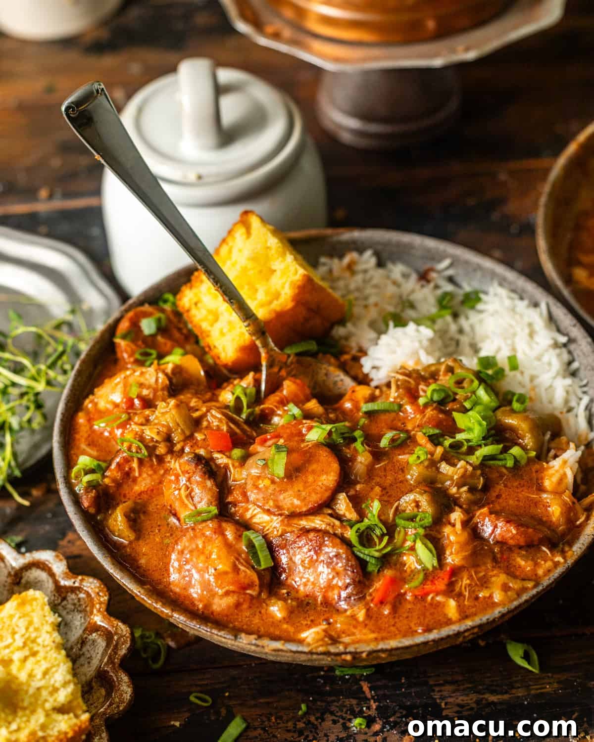chicken and sausage gumbo in a bowl with cornbread and white rice. 