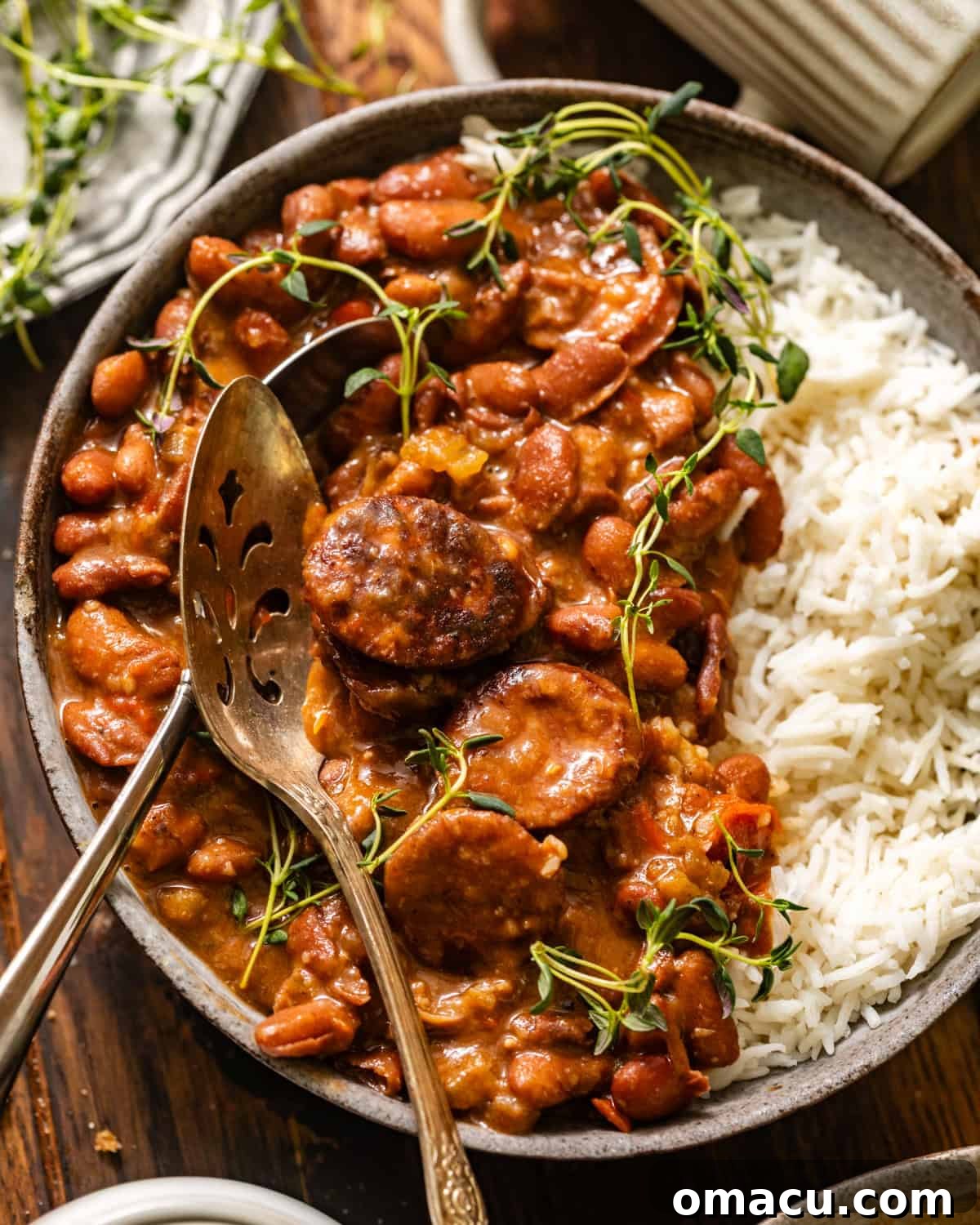overhead photo of cajun red beans and rice in a bowl with a spoon, garnished with fresh green onions.