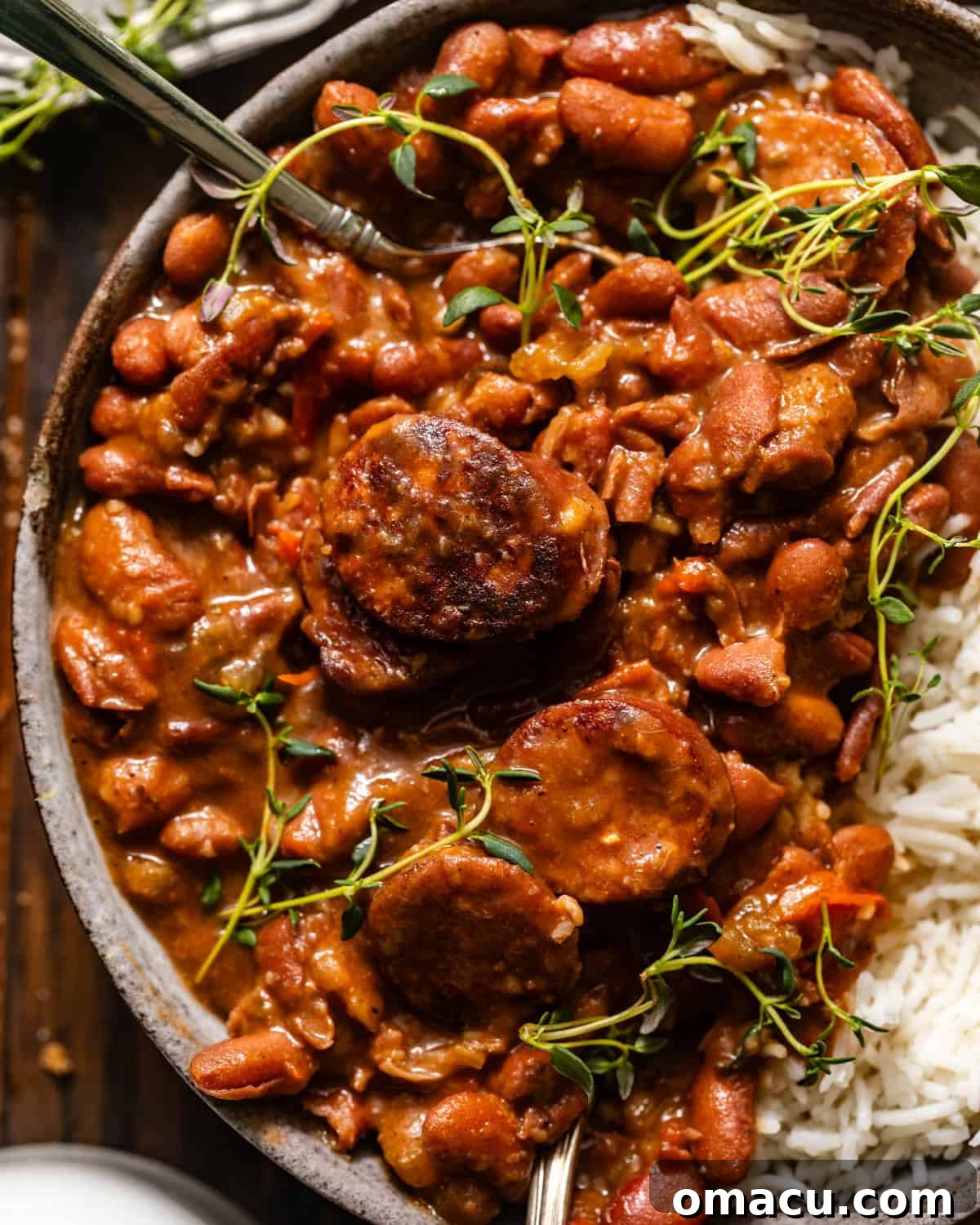 A bowl of rich red beans and rice, garnished with fresh sliced green onions, ready to serve.