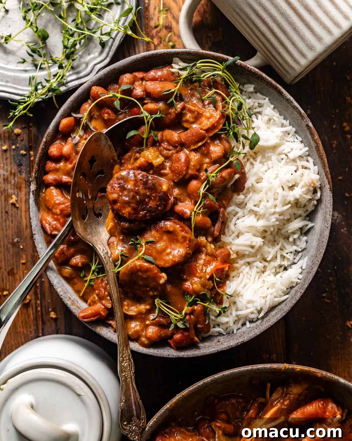 An inviting overhead photo of a bowl of red beans and rice, perfectly garnished, with a spoon ready for digging in.