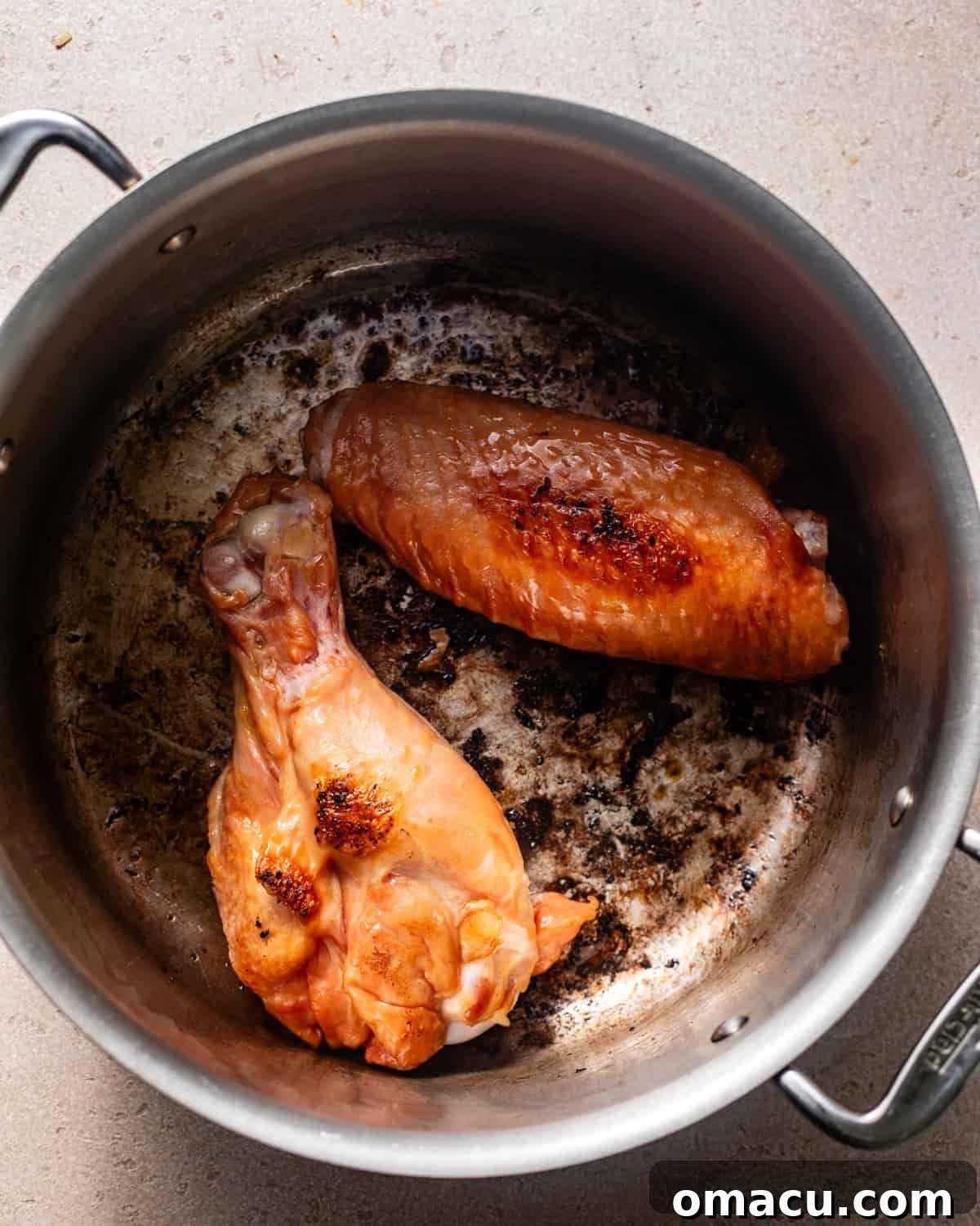 Smoked turkey legs being seared in the same pot after the sausage, building layers of flavor.