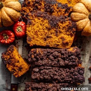 Pumpkin chocolate chip bread on a piece of parchment paper, surrounded by pumpkins.