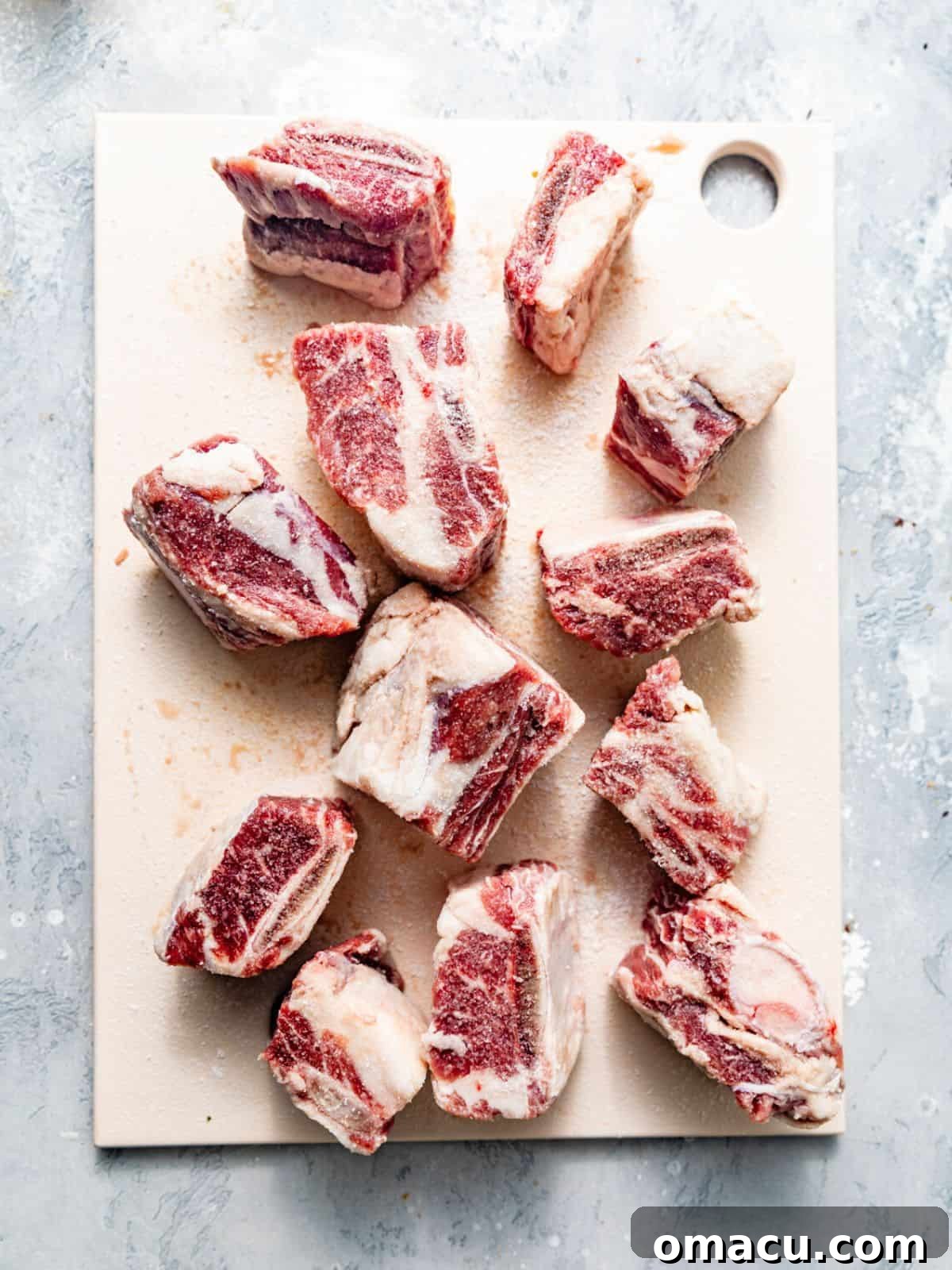 Short ribs arranged on a cutting board, patted dry with paper towels and generously seasoned with salt, black pepper, and garlic powder.