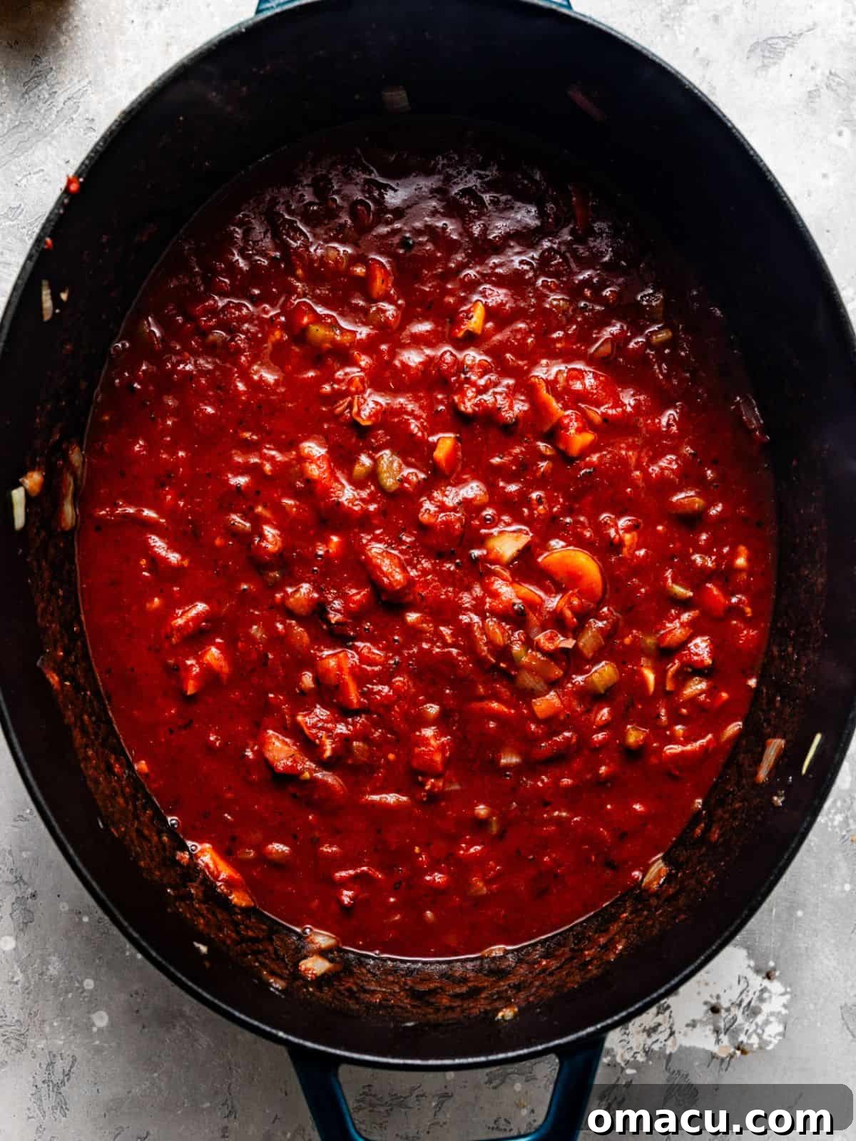 The braising liquid, a rich mixture of red wine and beef broth, is poured into a large pot, ready for the short ribs.