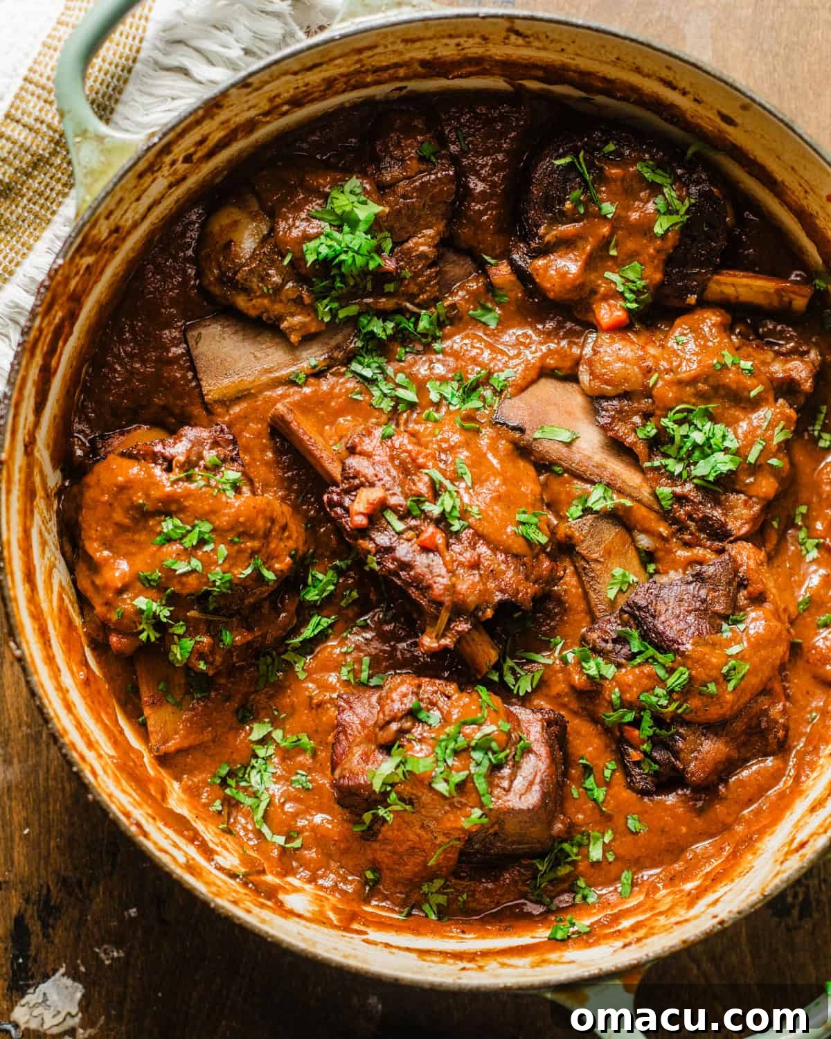 Braised short ribs in a pot, generously covered with a rich, glossy red wine reduction sauce.