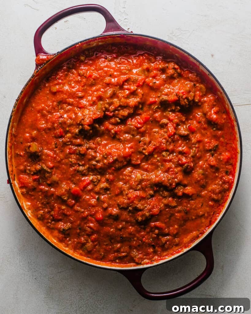 Rich tomato meat sauce simmering in a pot, ready for the baked ziti.