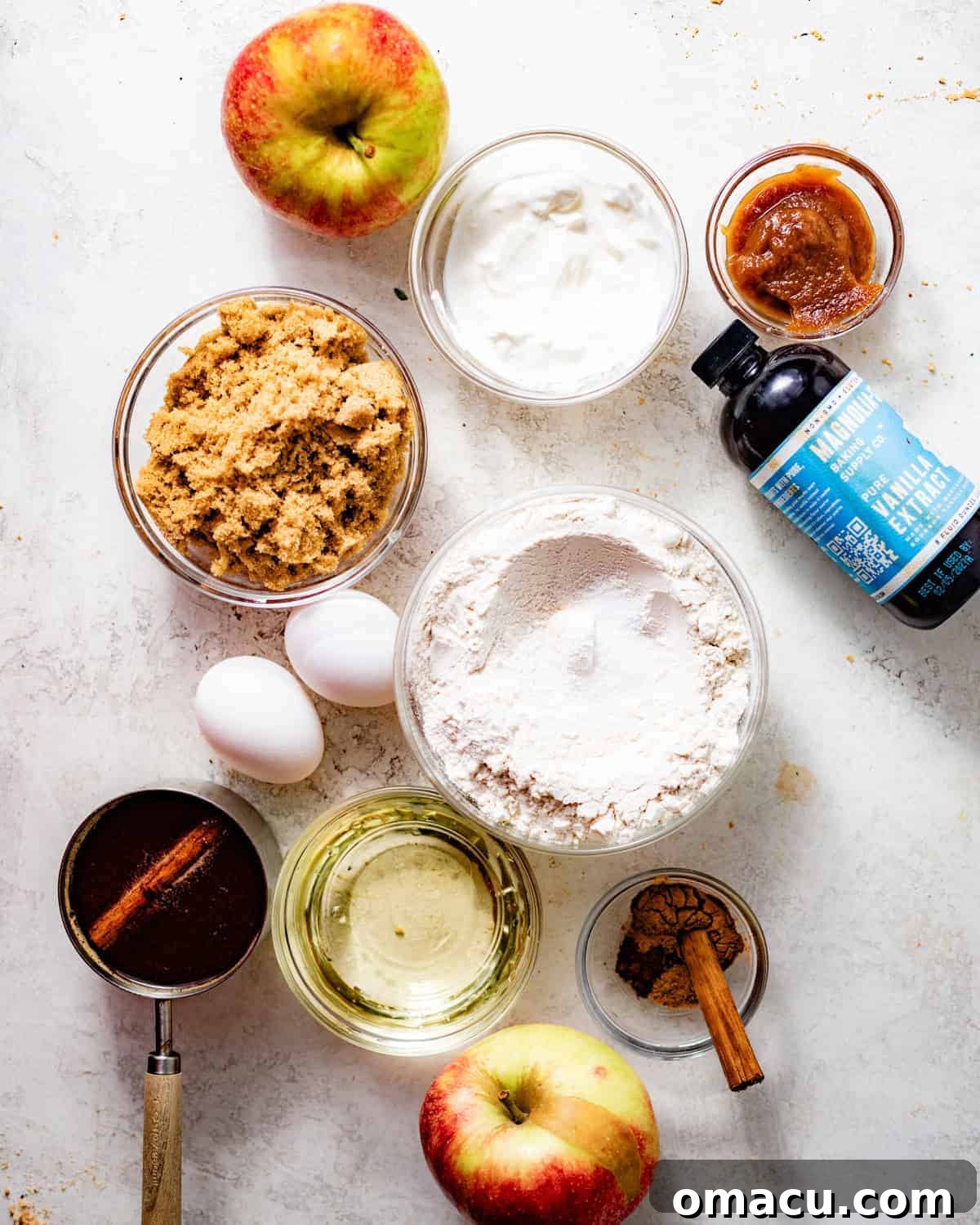A vibrant flat lay showcasing all the fresh, high-quality ingredients needed to bake a delicious apple cider bundt cake, arranged on a clean white surface.