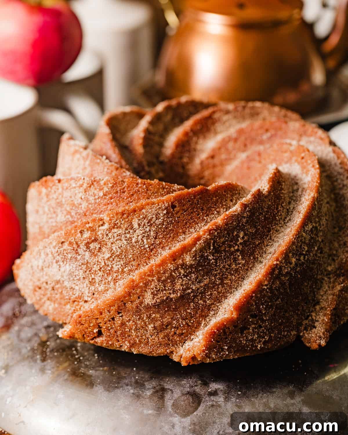 The finished Apple Cider Bundt Cake, beautifully coated in sparkling cinnamon sugar and drizzled with browned butter, showcasing its golden-brown crust.