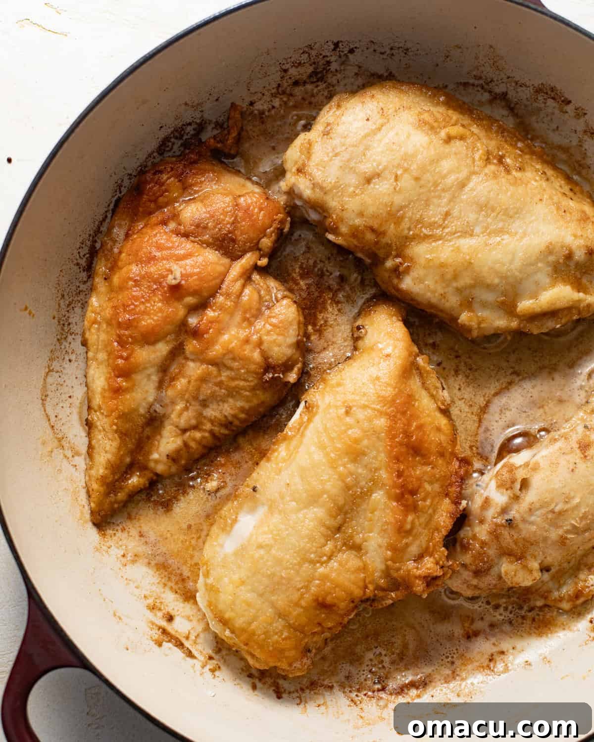 Golden-brown, pan-seared chicken sizzling in a large skillet, ready to be removed.