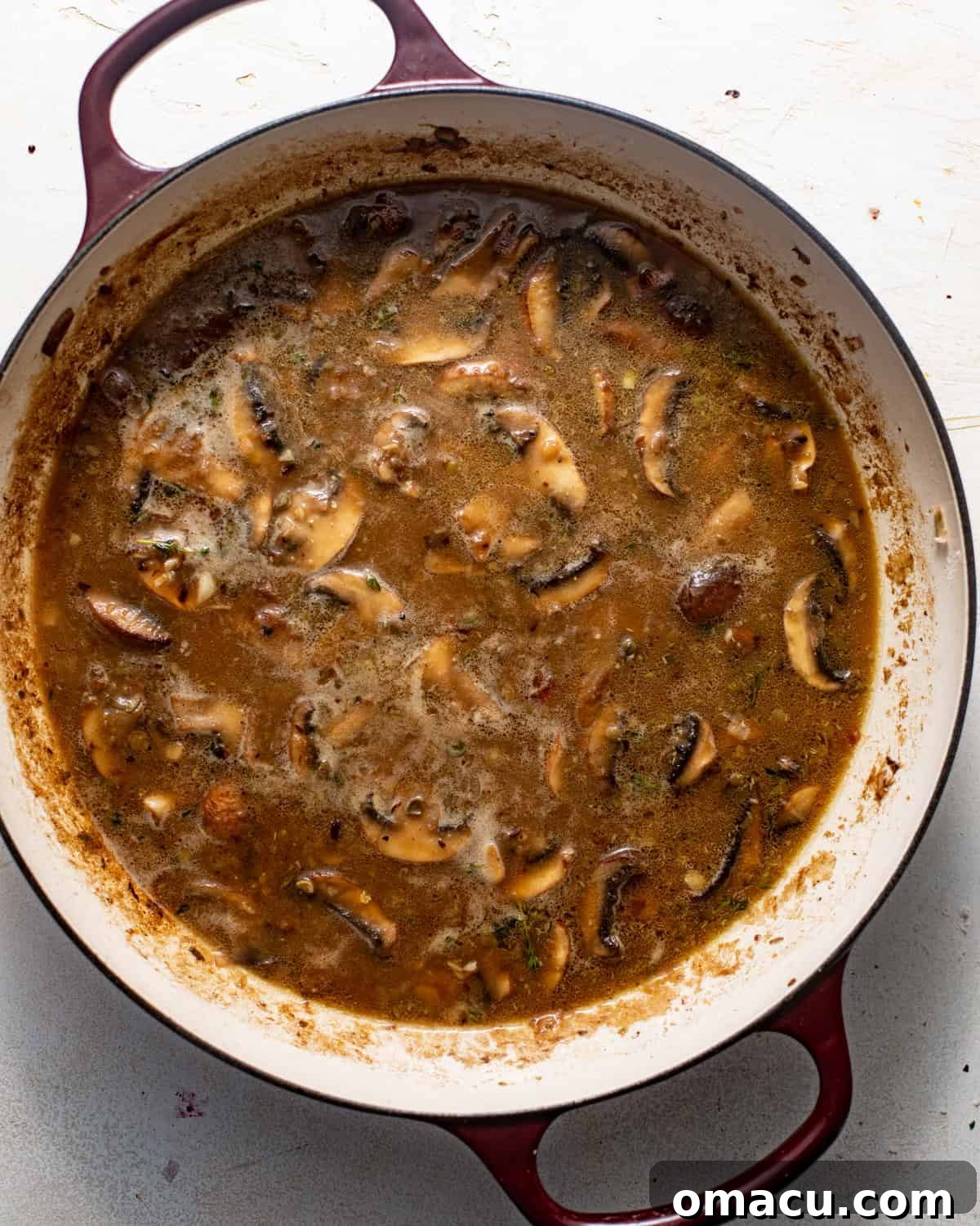 A rich, creamy chicken marsala sauce with mushrooms simmering in a pan.