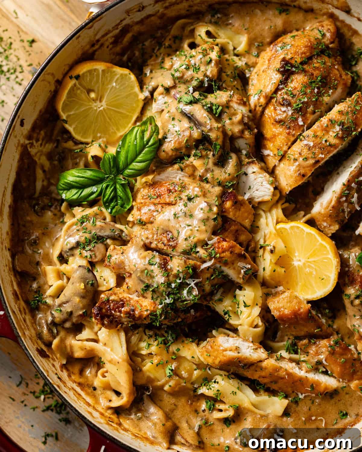 An overhead shot of a skillet filled with creamy Chicken Marsala Fettuccine, generously garnished with freshly grated Parmesan cheese and vibrant basil leaves, ready to be served.