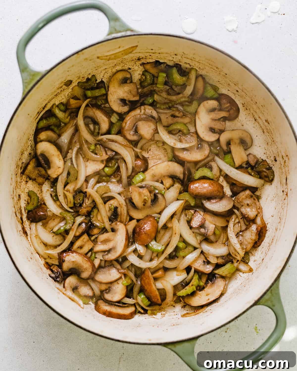Diced celery, sliced onions, mushrooms, and minced garlic sautéing in a skillet, gently browning.