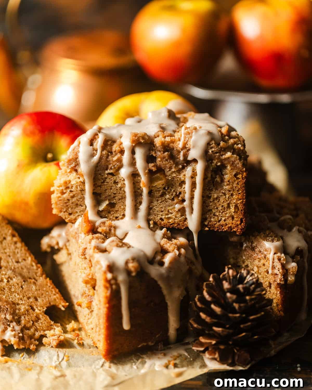 Slices of delicious apple coffee cake on parchment paper with fresh apples in the background.