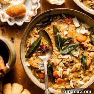 creamy chicken and wild rice soup in a bowl with a spoon, topped with sage and parmesan.