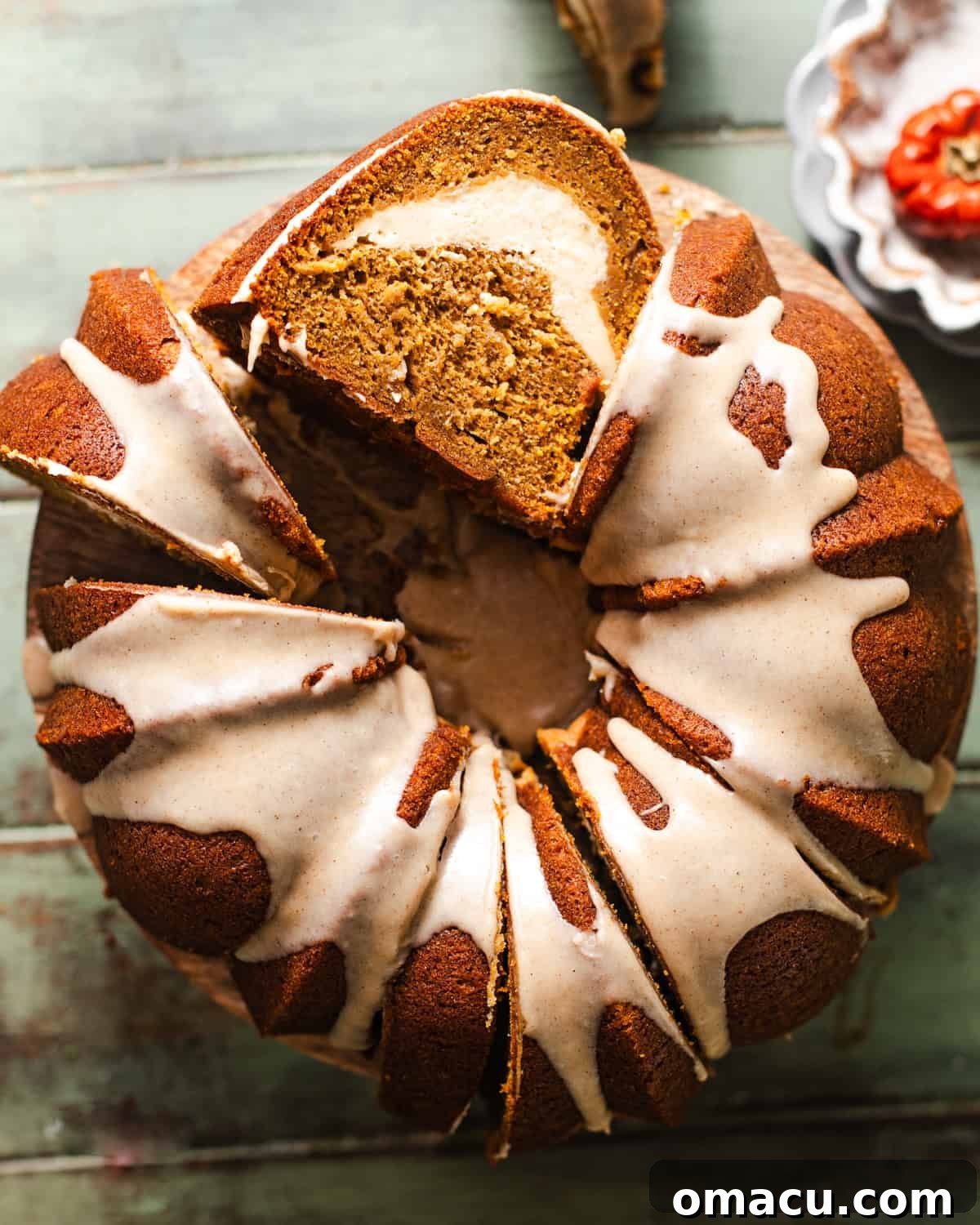 A beautifully sliced pumpkin pound cake on a cake stand, revealing its rich texture and a creamy white cheesecake swirl in the center, ready to be enjoyed.