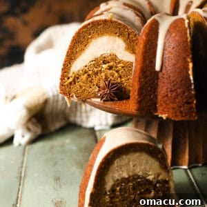 A delectable slice of pumpkin pound cake on a cake stand, revealing its moist crumb and the inviting swirl of cream cheese, ready to be served.