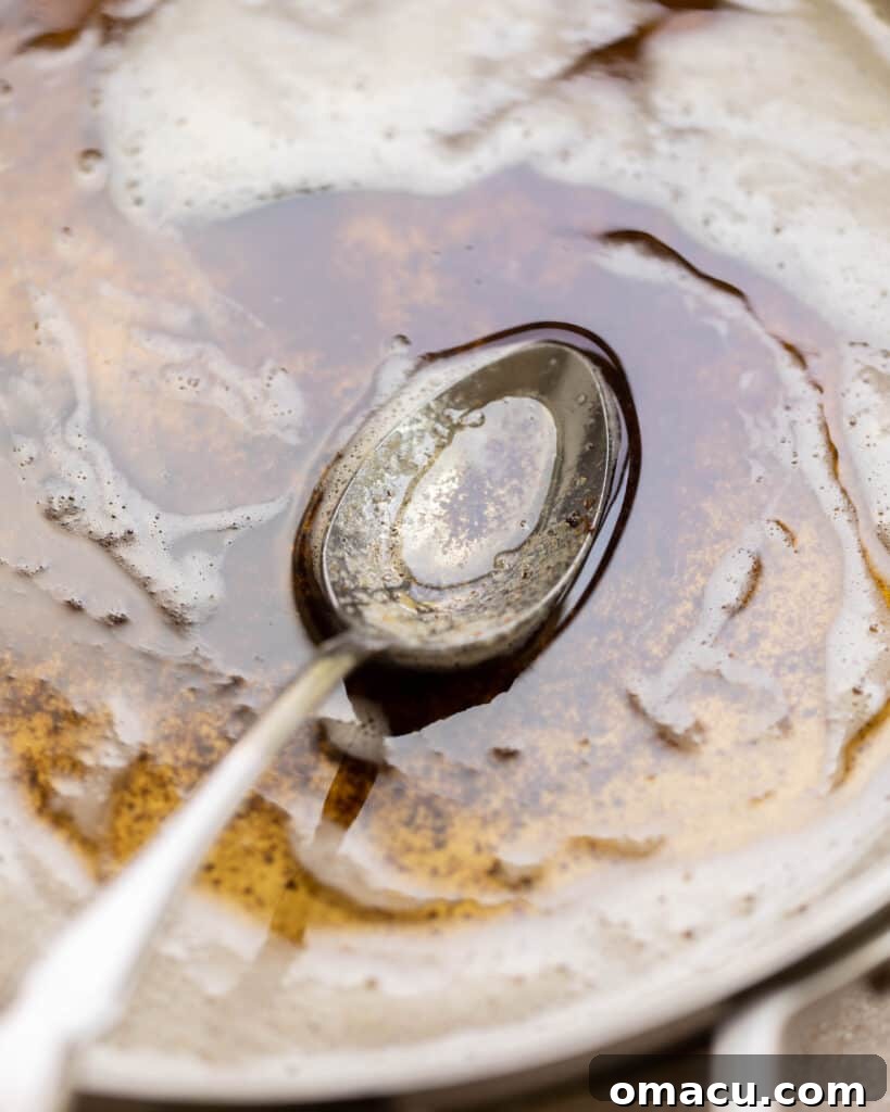 Browned butter in a small skillet with a spoon, showing the rich amber color and nutty aroma that makes for a delicious glaze.