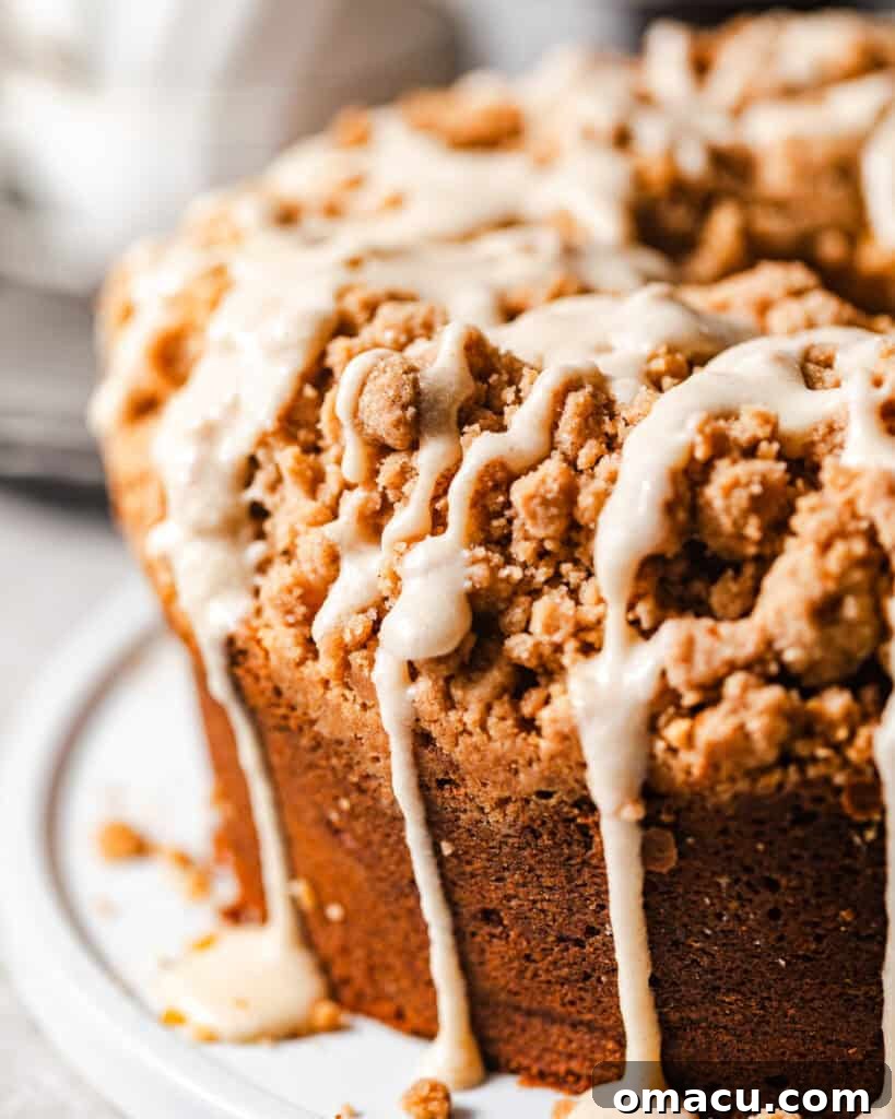 A beautifully baked Coffee Cake Bundt Cake resting on a serving plate, being elegantly drizzled with the warm, rich brown butter glaze, creating a tempting finish.