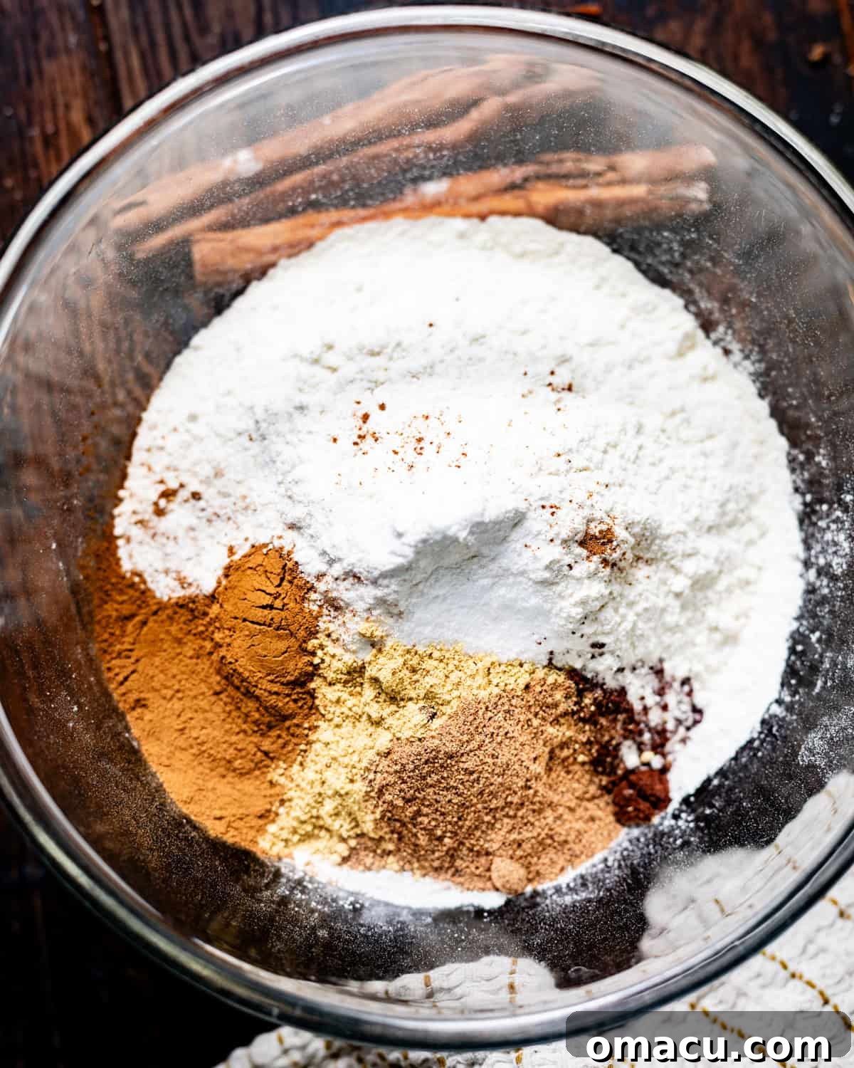 Dry ingredients, including all-purpose flour, baking powder, baking soda, kosher salt, cinnamon, nutmeg, ground ginger, allspice, and ground cloves, are thoroughly whisked together in a medium mixing bowl, ensuring an even distribution of flavor before being combined with wet ingredients.