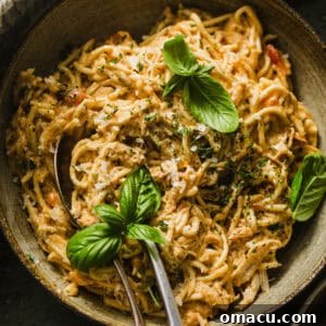 slow cooker chicken spaghetti in a bowl with a fork and spoon, ready to be enjoyed.
