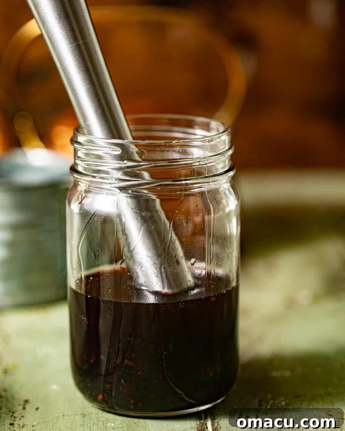 The initial ingredients for the Witches Brew cocktail: muddled blackberries, maple syrup, bourbon, and triple sec, carefully combined in a small glass jar.