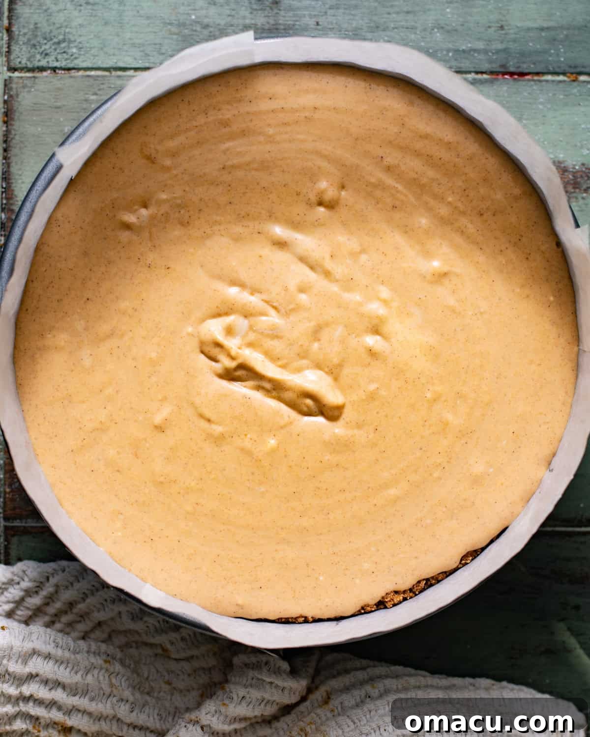pumpkin cheesecake batter poured into the cooled graham cracker crust prior to baking in the oven. 