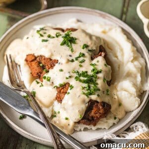 Classic country fried steak on a plate, perfectly covered in a rich, creamy white gravy, ready to be enjoyed.