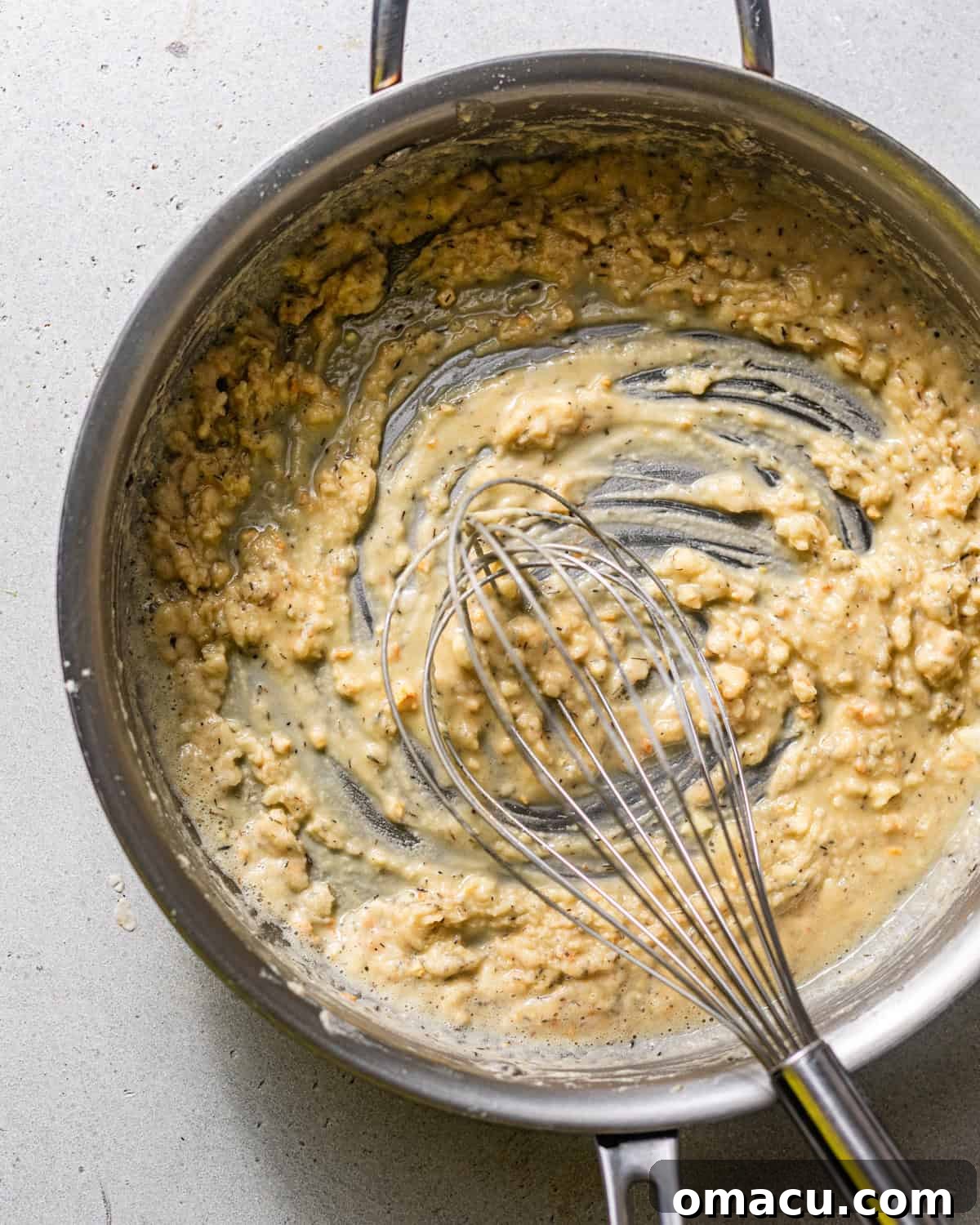 Butter melting and flour being whisked in a skillet, forming the base for a rich and creamy white gravy.