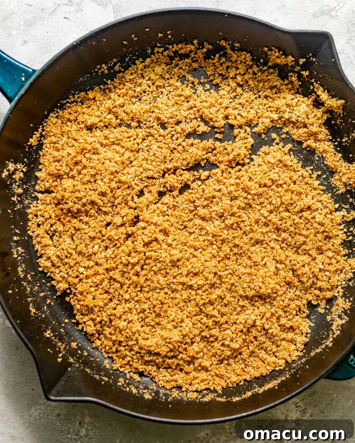 Golden brown Panko breadcrumbs being toasted in a skillet with melted butter for the topping.