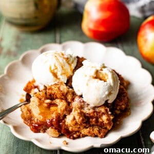 apple cobbler on a plate with ice cream and a spoon.