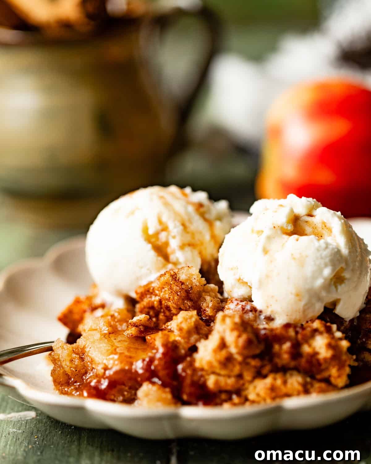 A slice of warm apple cobbler on a plate, topped with a melting scoop of vanilla ice cream, ready to be enjoyed.